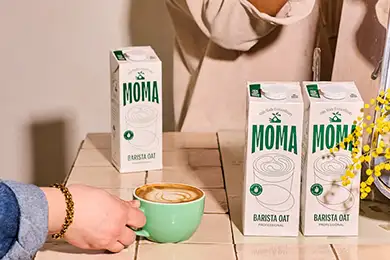MOMA Barista Oat Milk with a cup of coffee.