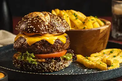 Beef burger topped with cheese and served with fries.