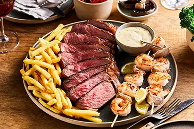 Plated sirloin steak with prawns and fries.